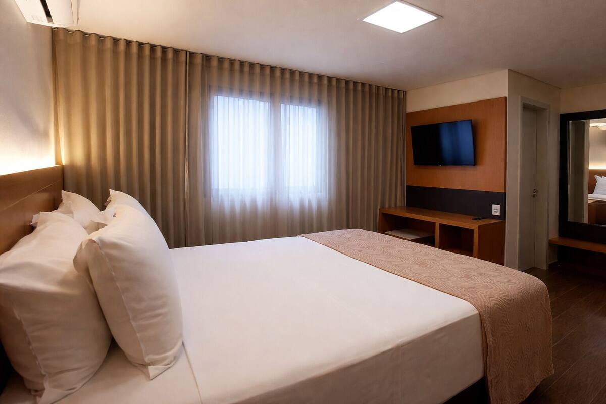 Une chambre d’hôtel avec un grand lit, un bureau, un téléviseur à écran plat et un miroir.