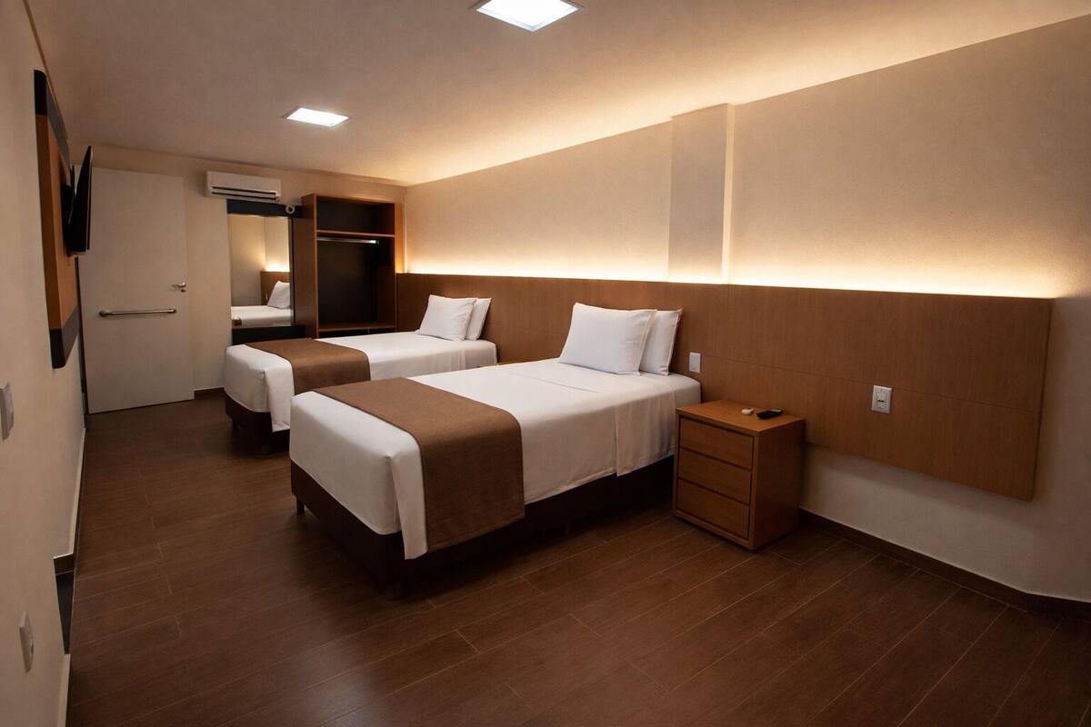 Une chambre d’hôtel avec deux lits, une armoire, une table de chevet et un téléviseur.