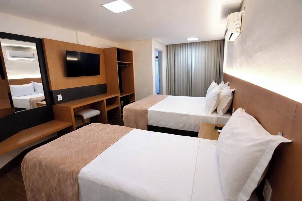 Une chambre d’hôtel avec deux lits, une télévision, un bureau et un miroir.