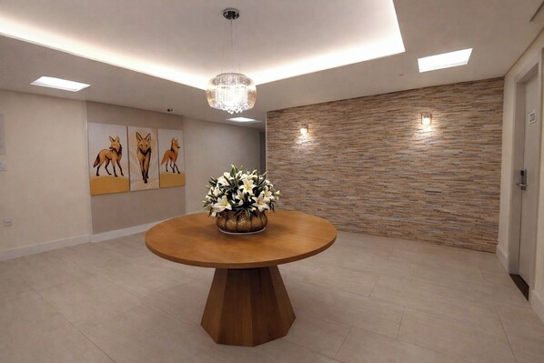 Een moderne eetruimte met een ronde tafel, een kroonluchter en een wand met houten lambrisering.