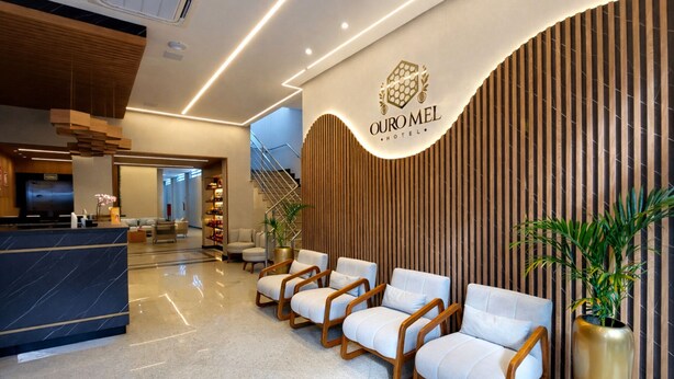 A modern hotel lobby with a reception desk, seating area, and a staircase. - HOTEL OURO MEL (Santa Bárbara)