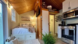 A cozy bedroom with a bed, bedside table, and a potted plant.