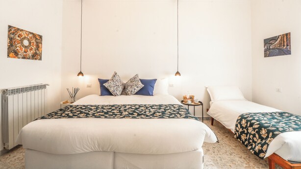 A hotel room with a large bed, two bedside tables, a radiator, and two wall-mounted lamps. - Apartment with balcony near Maradona Stadium (Napoli)