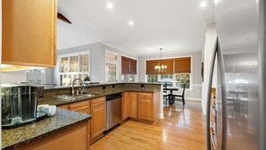 A modern kitchen with wooden cabinets, granite countertops, and a built-in dishwasher.