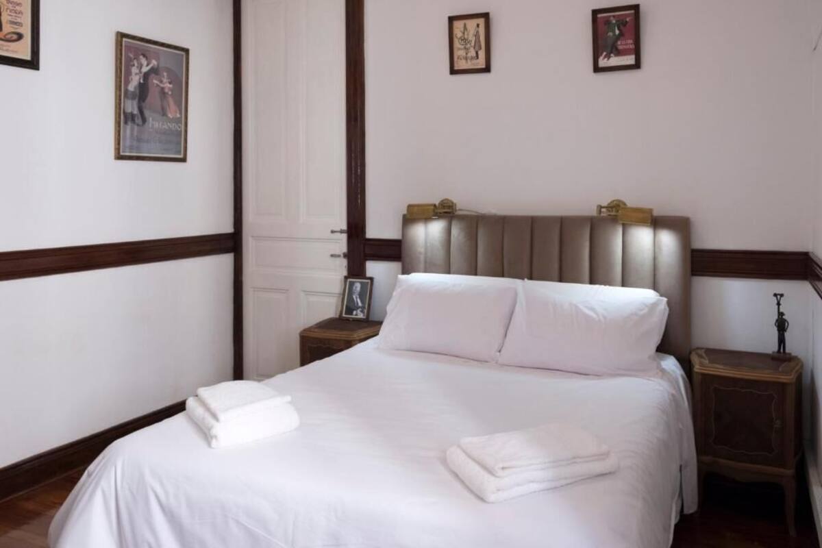 A hotel room with a bed, a nightstand, and a framed picture on the wall.