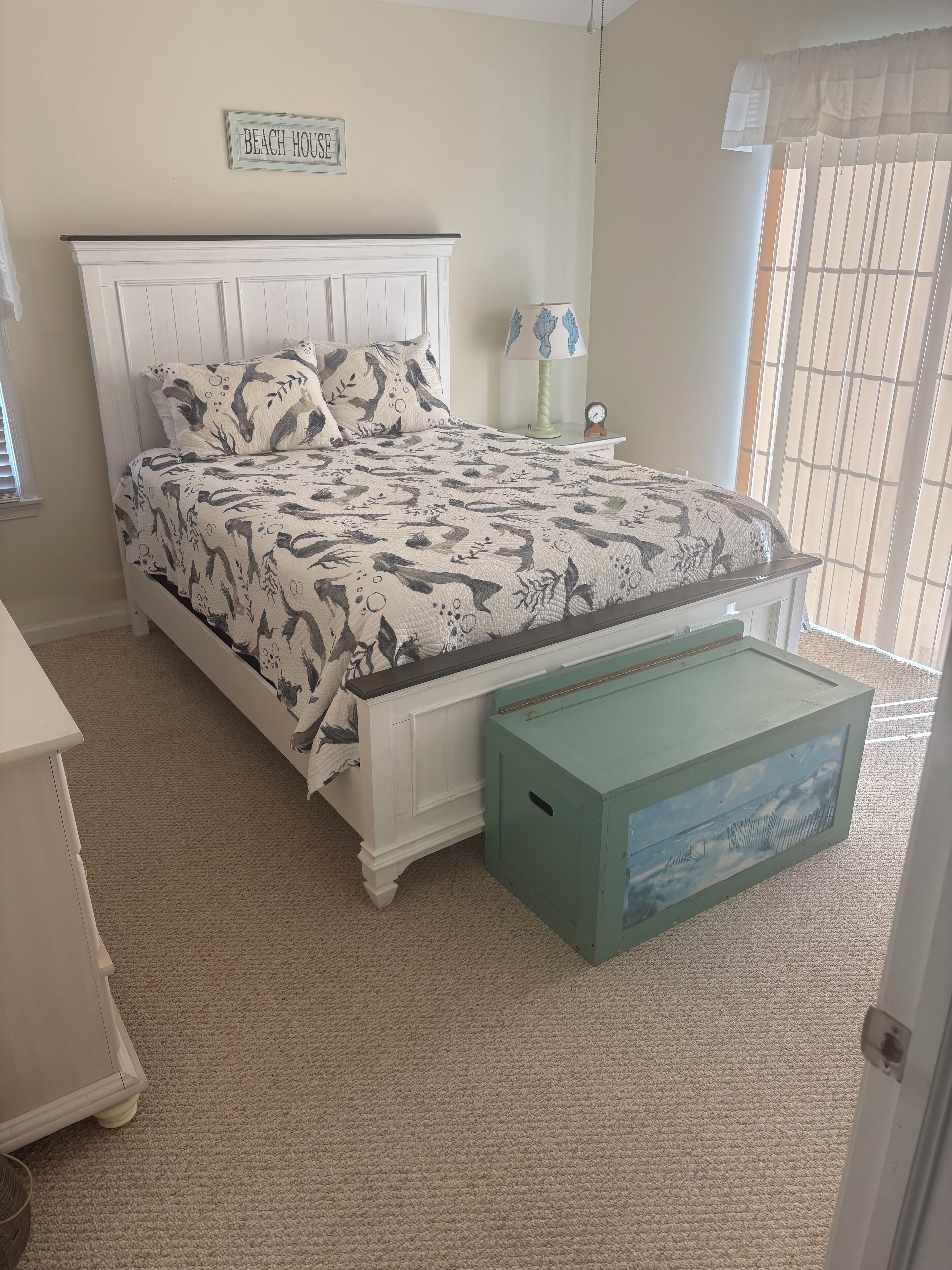 Un dormitorio con una cama, una mesita de noche, una lámpara y un cartel que dice "BEACH HOUSE".