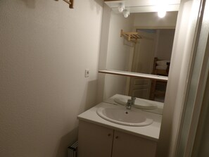 Een badkamer met een wit wastafel, een spiegel en een handdoekhouder.