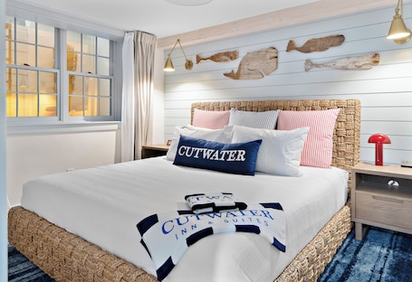 A bed with a white and blue blanket, a headboard with a woven design, and a wall with wooden panels and fish decorations.