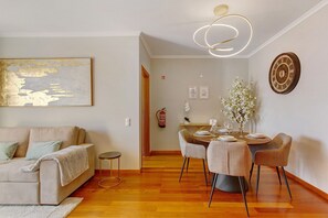 Una sala moderna con un sofá, una mesa de comedor para cuatro personas y una decoración minimalista.