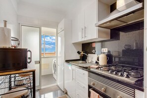 Una cocina moderna con estufa, pileta y alacenas blancas.