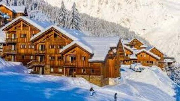 Eine Holzhütte mit mehreren Hütten, umgeben von schneebedeckten Bergen.