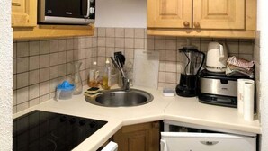 Eine kleine Küche mit Holdekor, einer Mikrowelle, einem Spülbecken, einem Herd und einem Kühlschrank.