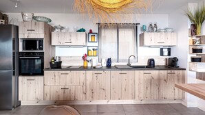 Una cucina moderna con mobili in legno, forno a microonde integrato e un'isola ampia con lavello.