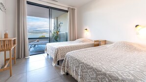 Una camera da letto con due letti, un balcone e vista mare.