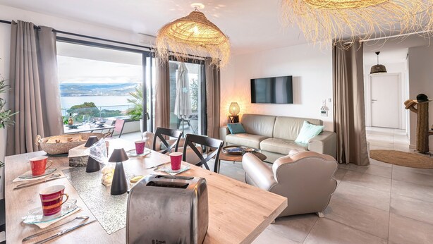 Un soggiorno moderno con zona pranzo, ampie finestre e una lampadario elegante.