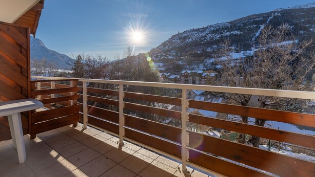 A wooden balcony with a view of a snow-covered mountain and a clear sky. - Le Parc Neige - Vue Montagne (Briancon)