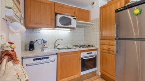 A kitchen with wooden cabinets, a microwave, a stainless steel refrigerator, a dishwasher, and a stove. - Le Parc Neige - Vue Montagne (Briancon)