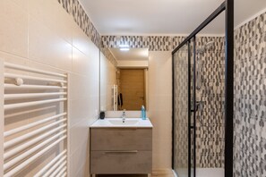 A bathroom with a white sink, a mirror, a towel rack, and a shower area. - Le Nid des Pyrénées - Proche des Angles (Fontrabiouse)