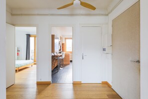 An open-plan living area with a dining table and chairs, a kitchen area, and a bedroom with a bed and a window. - Le Berthelot - Terrasse avec Vue Montagne (Grenoble)