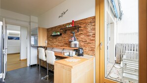 Una cucina compatta con un piano di lavoro in legno, una macchina da caffè e uno scaffale con utensili da cucina.