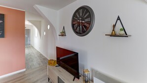 Un salon moderne doté d’un téléviseur à écran plat, d’une grande horloge murale et d’un décor minimaliste.