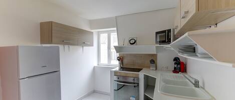 A modern kitchen with built-in appliances, a window, and a sink.