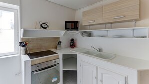 Une cuisine de taille réduite, équipée d’un four à micro-ondes, d’un évier et de meubles de rangement en bois.