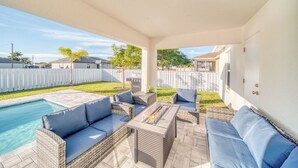 Un patio techado con mobiliario exterior, piscina y vista al vecindario.