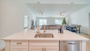 Una cocina amplia con una isla central, un comedor con un árbol de Navidad y una sala de estar con sofá y televisor.