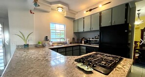 A kitchen with a granite countertop, a gas stove, a black refrigerator, and a window providing natural light.