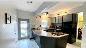 Una cocina moderna con una isla central, muebles oscuros y una estufa integrada.