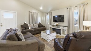 Ein Wohnzimmer mit einer Sofagarnitur, einem Couchtisch, einem Flachbildfernseher und einem Kamin.