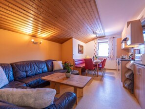 Ein gemütliches Wohnzimmer mit einer Ledersofa, einem Holztisch und einem Essbereich mit roten Stühlen.