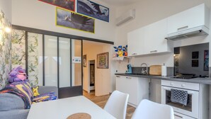 Una cocina moderna con armarios blancos, horno integrado y comedor con mesa y sillas blancas.