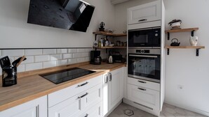 A modern kitchen with white cabinetry, a wooden countertop, a built-in oven, a microwave, and a wall-mounted TV. - La Closerie blanche - 5km Le Mans - Wifi (Yvré-l'Évêque)