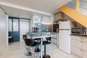 A modern kitchen with a central island, bar stools, and a microwave. - Panorama Marin - Parking - Mer (Bretignolles-sur-Mer)