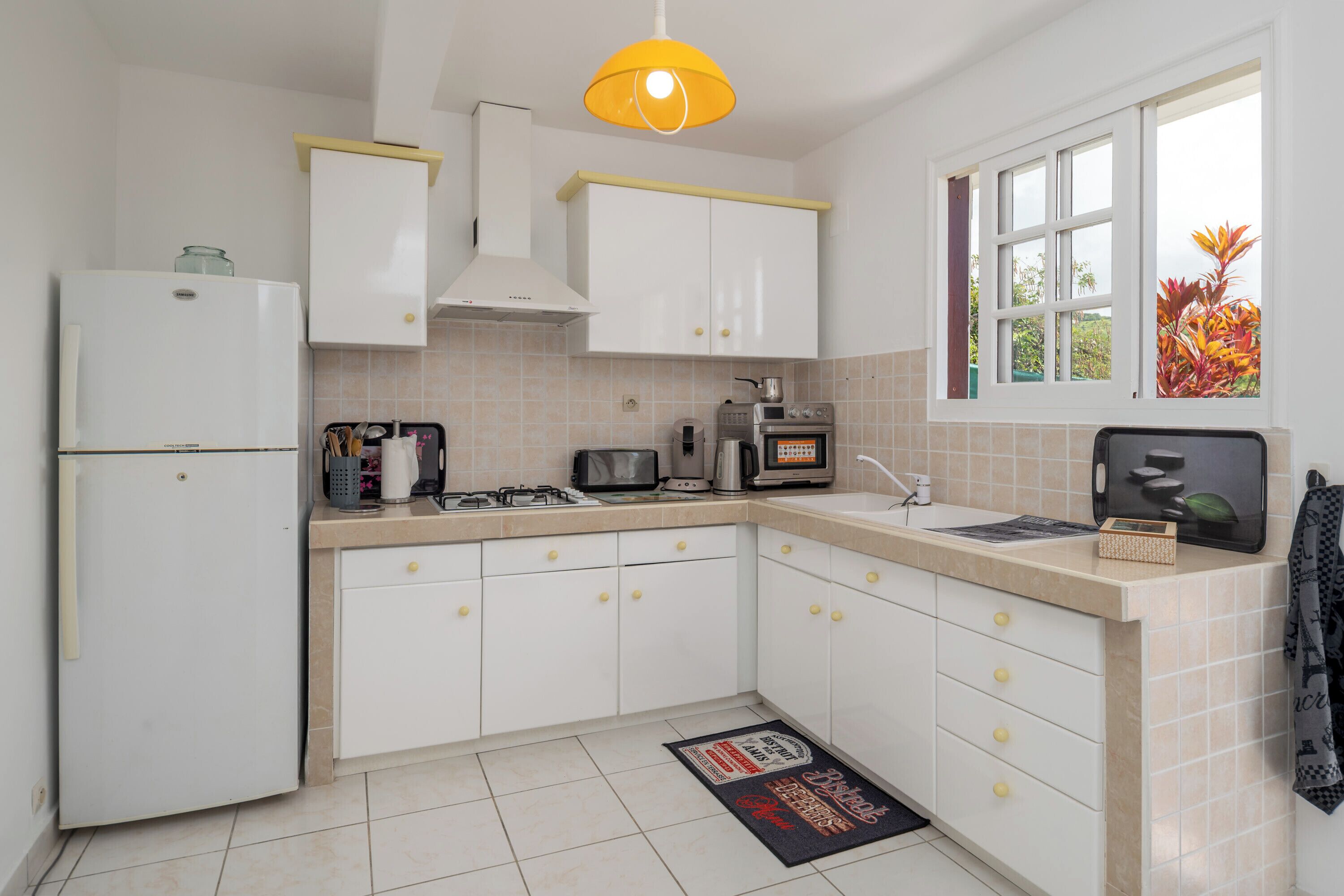 A kitchen with white cabinets, a refrigerator, a stove, a microwave, and a sink.