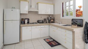 A kitchen with white cabinets, a refrigerator, a stove, a microwave, and a sink. - L’écrin - Climatisation - Jardin (Baillif)