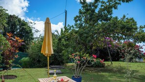 A patio with a wooden table, chairs, a yellow umbrella, and potted plants. - L’écrin - Climatisation - Jardin (Baillif)