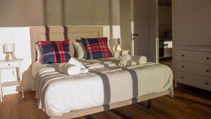 A neatly made bed with a plaid pillow, a bedside lamp, and a white nightstand. - CasadoZé - Ihr privates Ferienhaus mit Pool und Gartenblick in Arcos de Valdevez (Arcos de Valdevez)