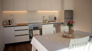 A compact kitchen with white cabinets, a built-in oven, and a refrigerator. - CasadoZé - Ihr privates Ferienhaus mit Pool und Gartenblick in Arcos de Valdevez (Arcos de Valdevez)
