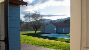 A view of a backyard with a swimming pool, a lawn, and a house with a red roof. - CasadoZé - Ihr privates Ferienhaus mit Pool und Gartenblick in Arcos de Valdevez (Arcos de Valdevez)
