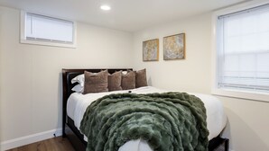 A bedroom with a bed, a window with blinds, and two wall-mounted artworks. - Walkable 1BR in Village of Horseheads, Near I-86, Corning & Finger Lakes (Horseheads)