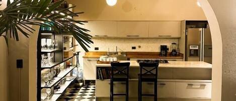 A kitchen with a checkered floor, an archway, and a bar area with stools.
