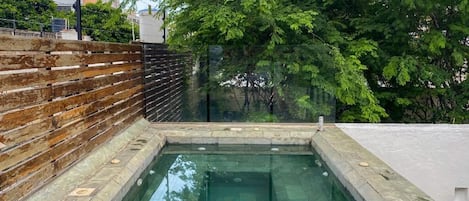A rectangular pool with stone tiles and a wooden fence.
