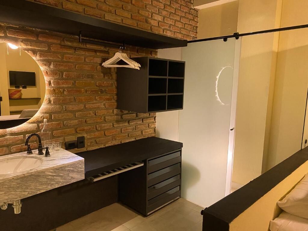 Ein modernes Badezimmer mit Marmorwaschbecken, einem schwarzen Waschtisch, einem hängenden Handtuchhalter und einer Ziegelwand.