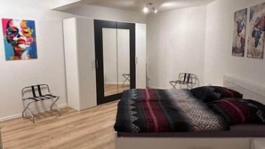 Une chambre à coucher comprenant un lit, une chaise, une armoire et des œuvres d’art accrochées aux murs.