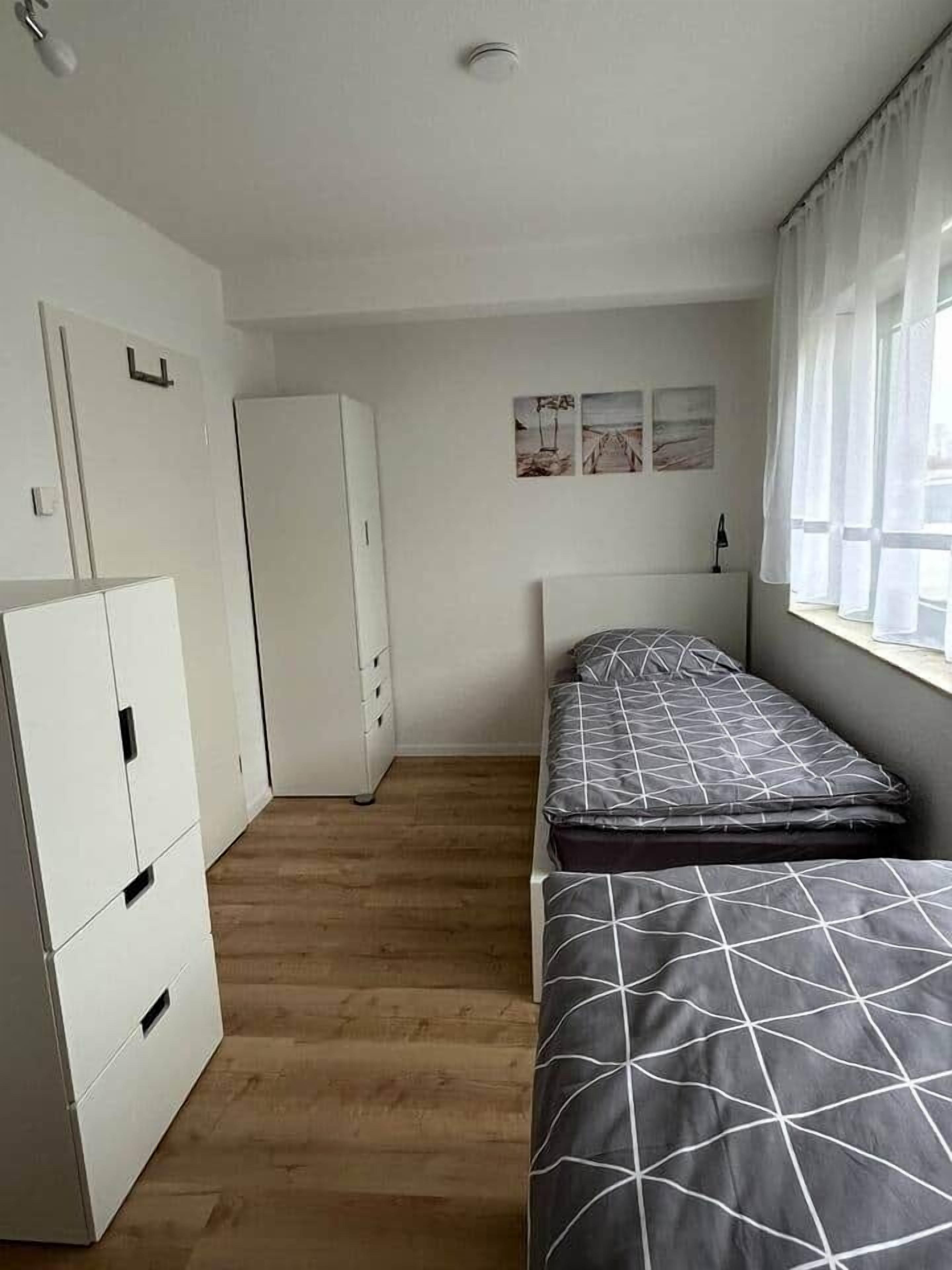 A compact bedroom with a bed, a wardrobe, and a window with curtains.