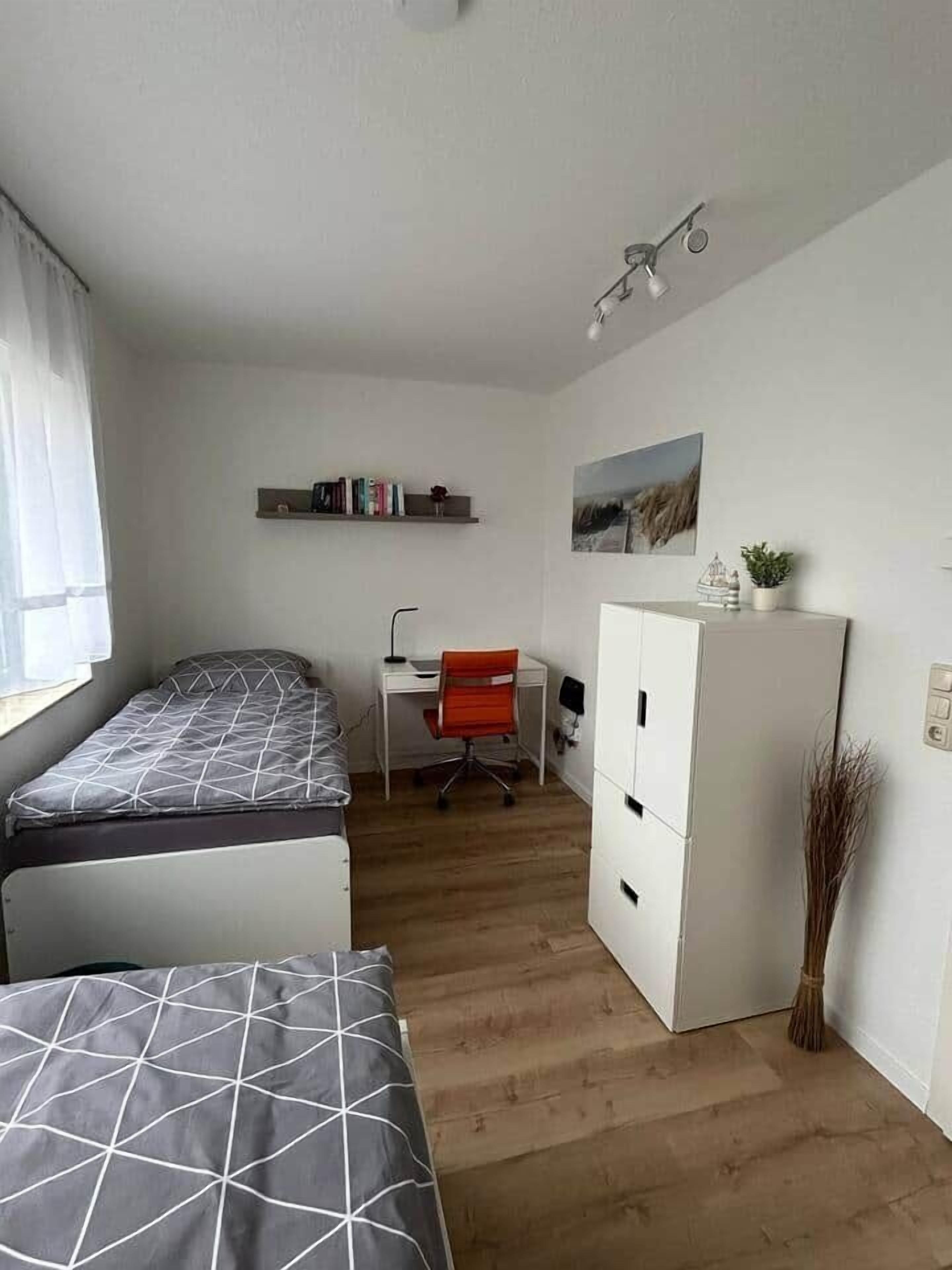 Ein kleines Zimmer mit Bett, Schreibtisch und Kleiderschrank.