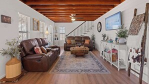 Ein gemütliches Wohnzimmer mit einer braunen Ledersofa, einem Holztisch und einer Treppe, die zu einer weiteren Ebene führt.